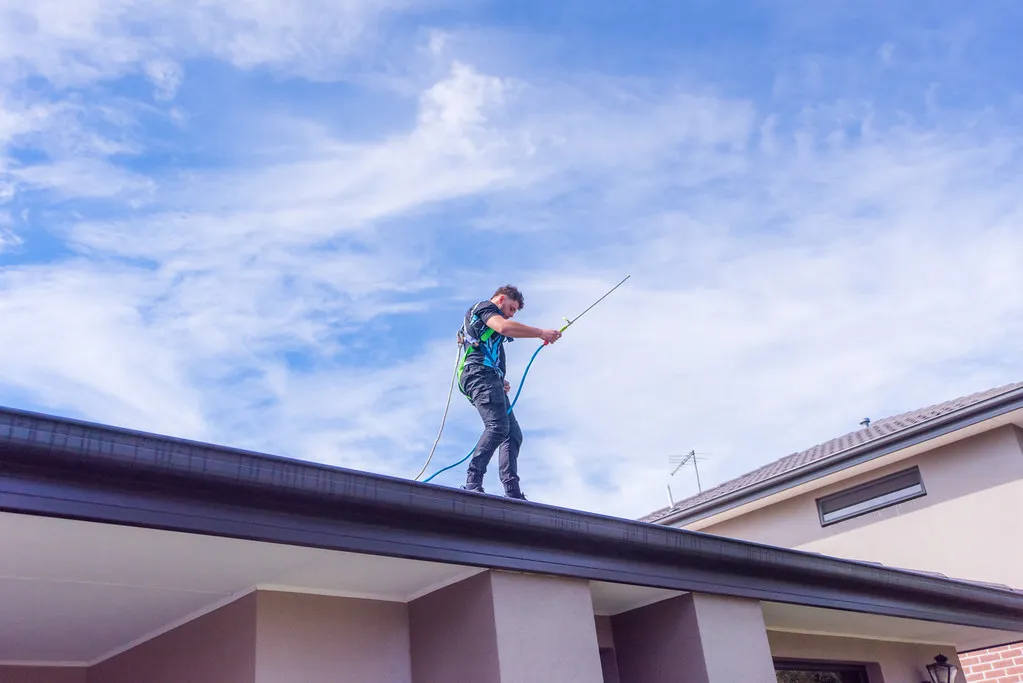 Standing on roof with gutter cleaning tools